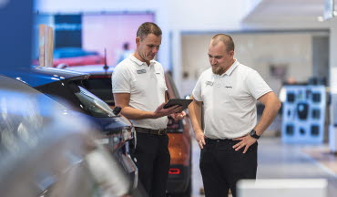 Två bilförsäljare tittar på en padda i bilhallen