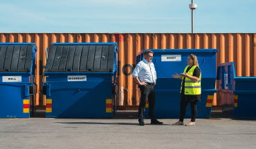 Företagskund och säljare från Tekniska verken pratar framför kundens sorteringscontainrar
