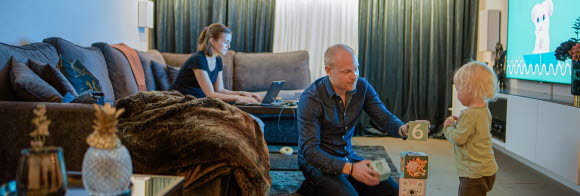 Pappa och dotter leker med klossar medan mamma jobbar på datorn