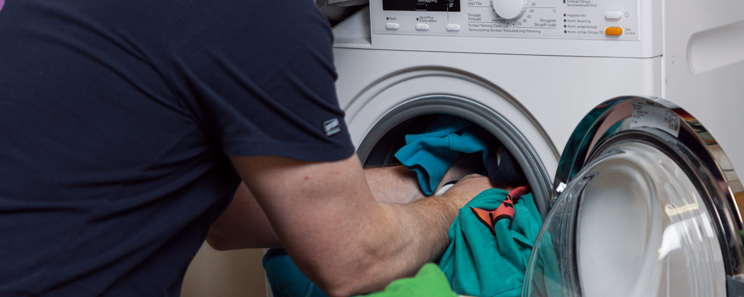 Person fyller en tvättmaskin med tvätt