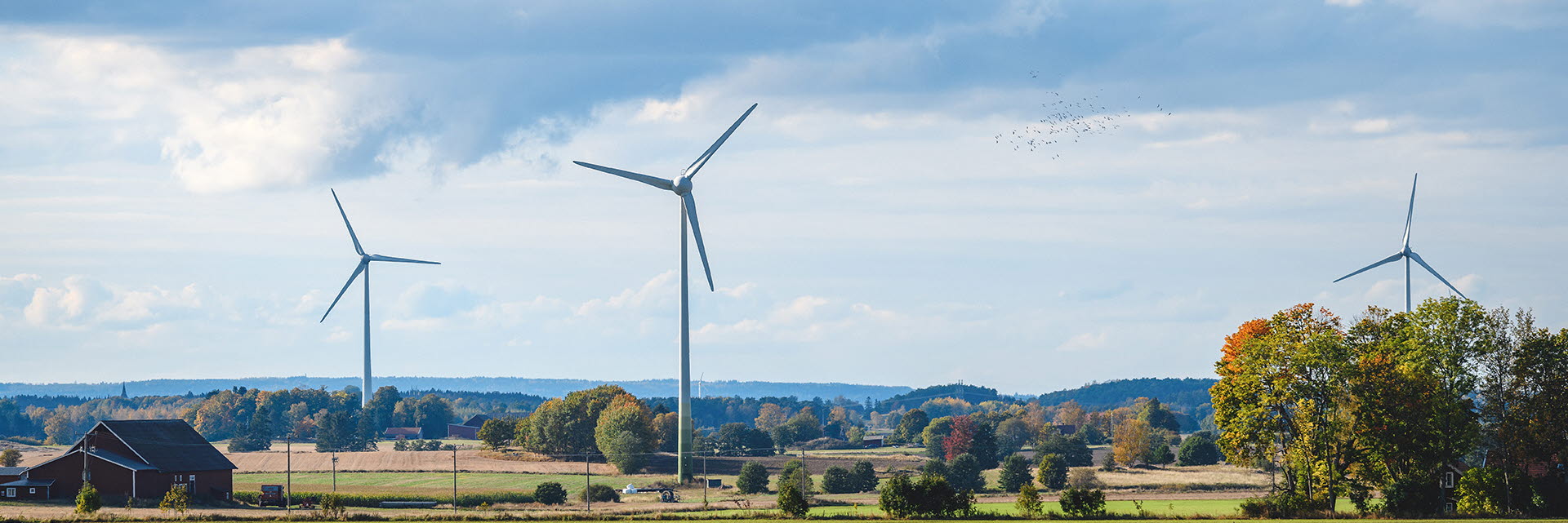 Vindkraftverk mot en blå himmel på slätten i Mjölby